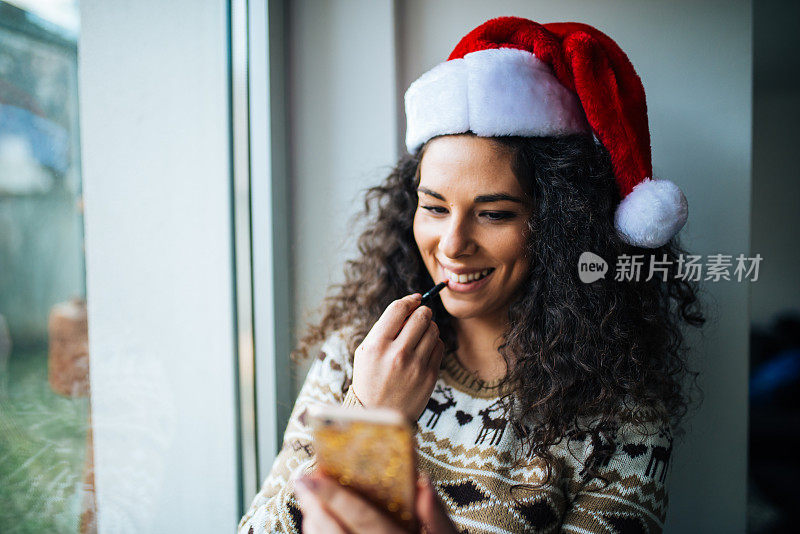 迷人的年轻女子在窗前化妆