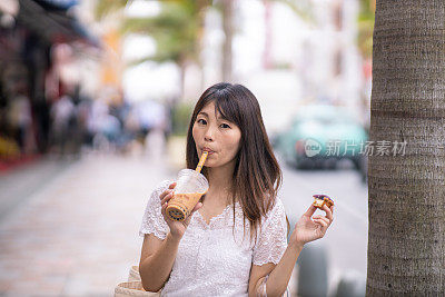 年轻女子在城市街道上喝着木薯饮料