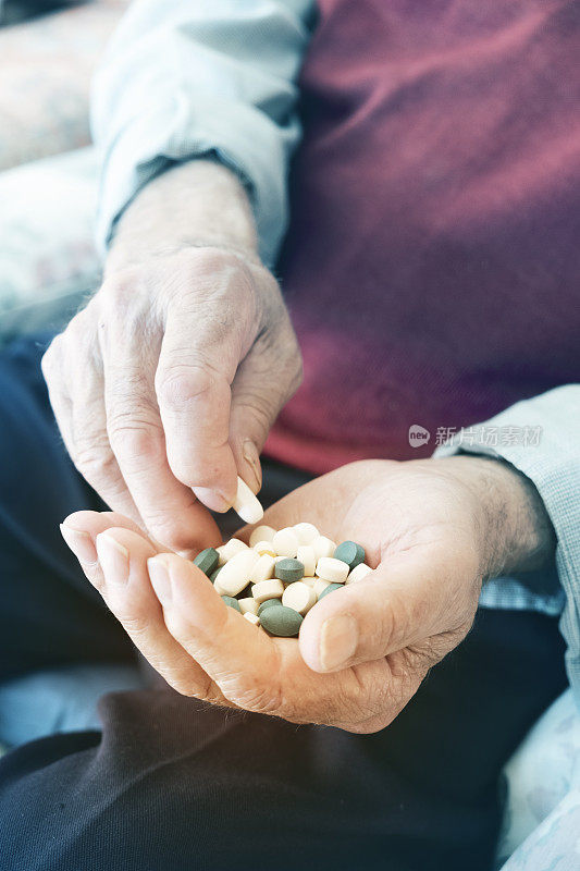 一个手里拿着一堆药丸的老人
