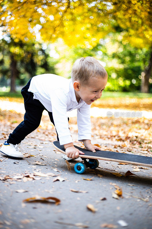 可爱的小男孩在公园里推滑板