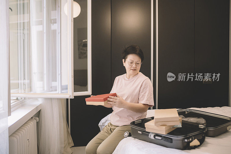 一位亚洲华裔女性在旅行前在房间里打包她的纪念品行李