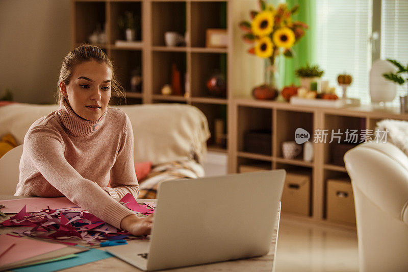 一名年轻女子正在查阅手工制作纸花的教程