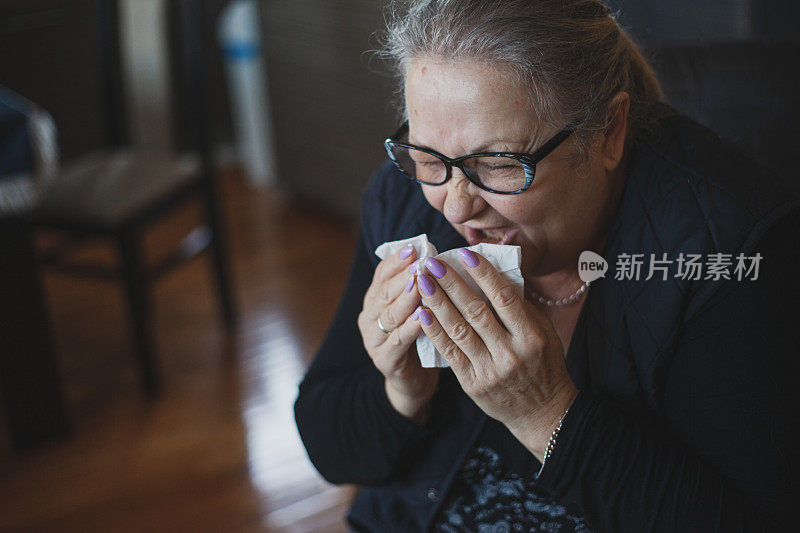 老年妇女过敏，用纸巾擤鼻子