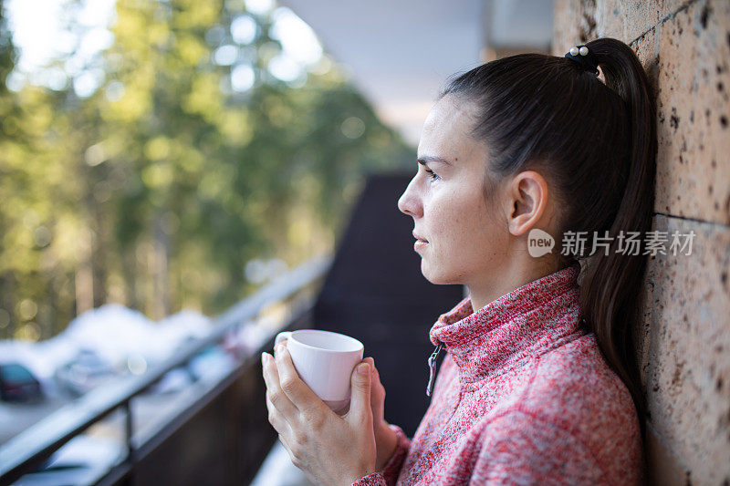 一个年轻的女人在山上的阳台上喝着早茶