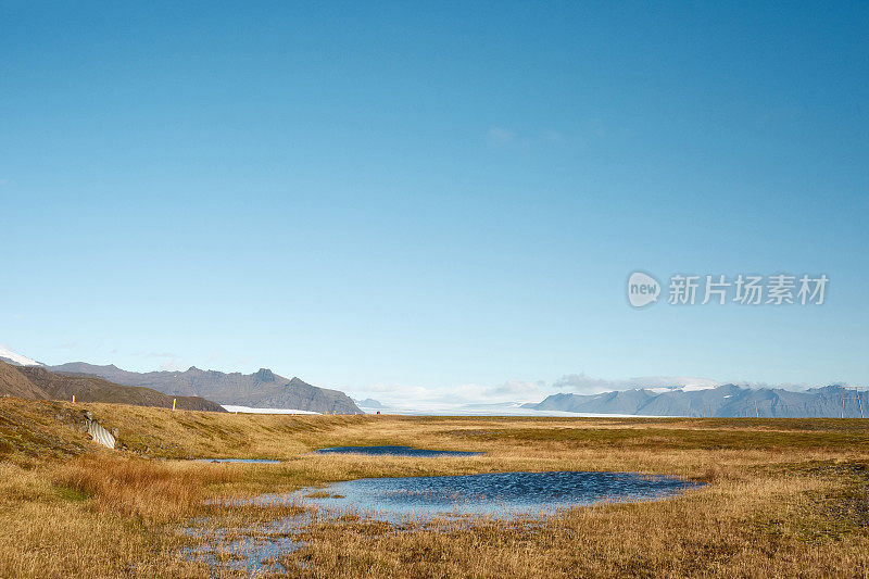 广阔的荒地和水池的风景背景清澈的蓝天和高山在远处，冰岛