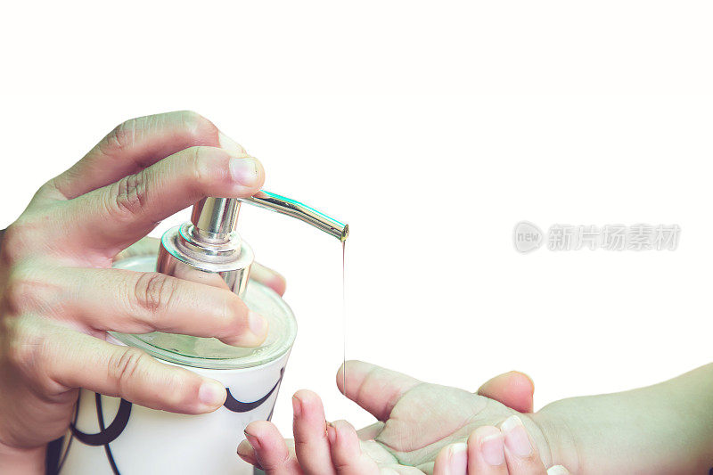 预防冠状病毒或COVID-19大流行，母亲把洗手液放在女儿手上。经常使用含酒精的洗手液洗手。家庭卫生的概念。