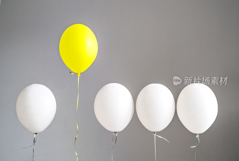 跳出固有观念。是不同的。勇敢。聪明的主意。一个独特的黄色气球突然从普通的灰色气球群中冒出来。