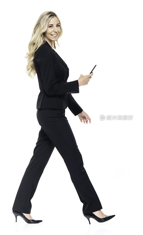 白人女性商务人员在白色背景下行走并使用智能手机