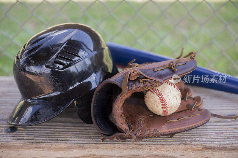 棒球赛季到了。教练席上的球棒、手套、头盔和球。