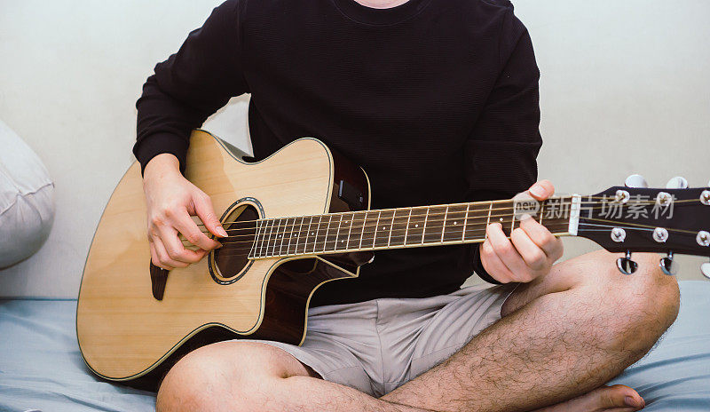 男人在床上弹吉他