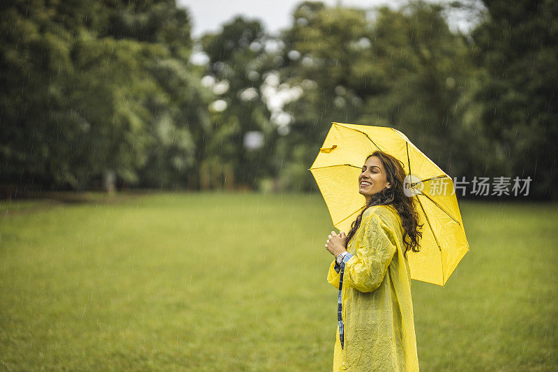 快乐的女人微笑着行走在雨天