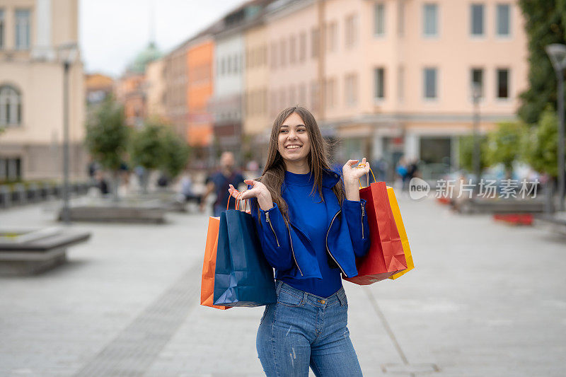 年轻快乐的女人带着购物袋走在街上