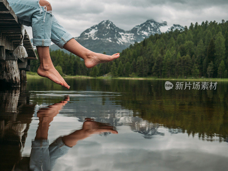 双脚悬在湖边码头上