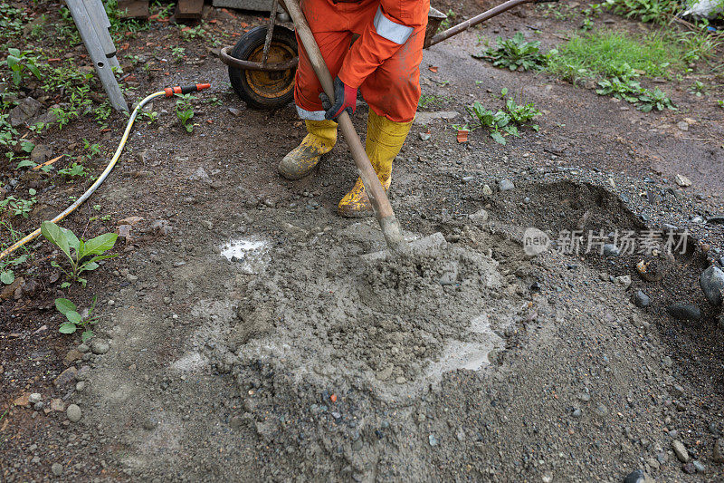 老建筑工人在现场用铲子搅拌混凝土、水泥和沙子