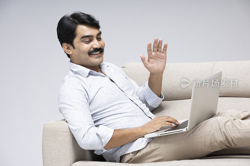成熟的男人坐在沙发在白色的背景，库存照片