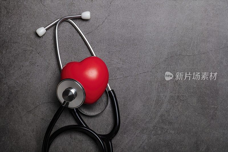 心脏健康保险概念，世界心脏日。听诊器与红色的心，灰色背景与文字空间。前视图。平的。
