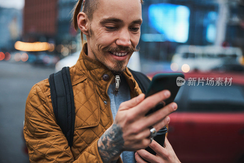 一个快乐的年轻人在户外用智能手机发短信