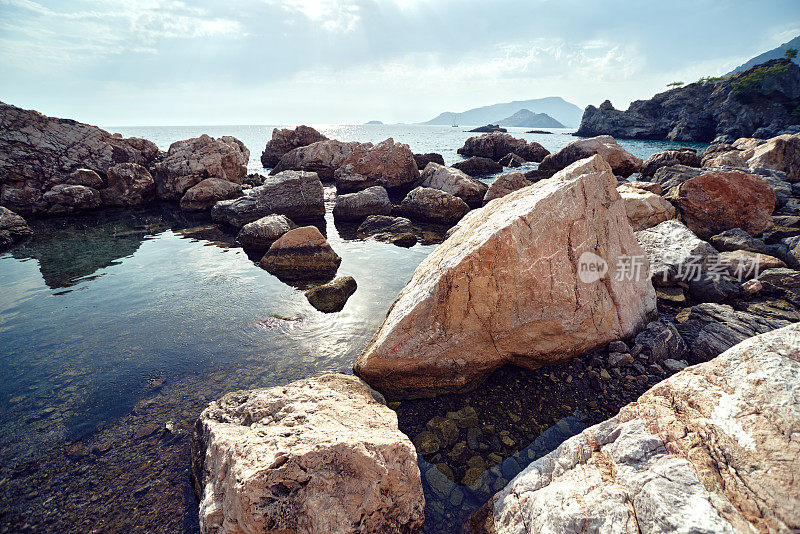 地中海岩石海岸。阳光反射在水中。背景光