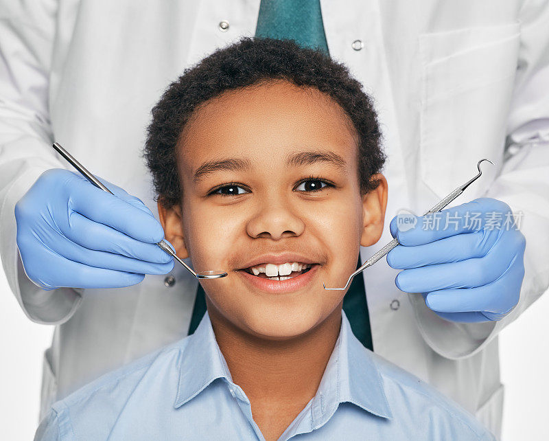 非裔美国男孩在儿童牙科诊所。儿童在牙医检查口腔时露出露出牙齿的微笑。特写镜头