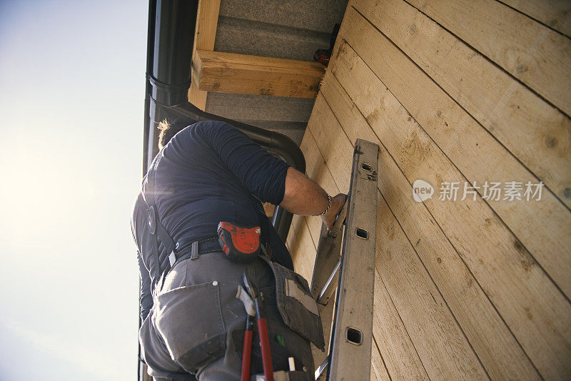 屋顶建筑工人用特殊的钳子完成金属排水沟的折叠