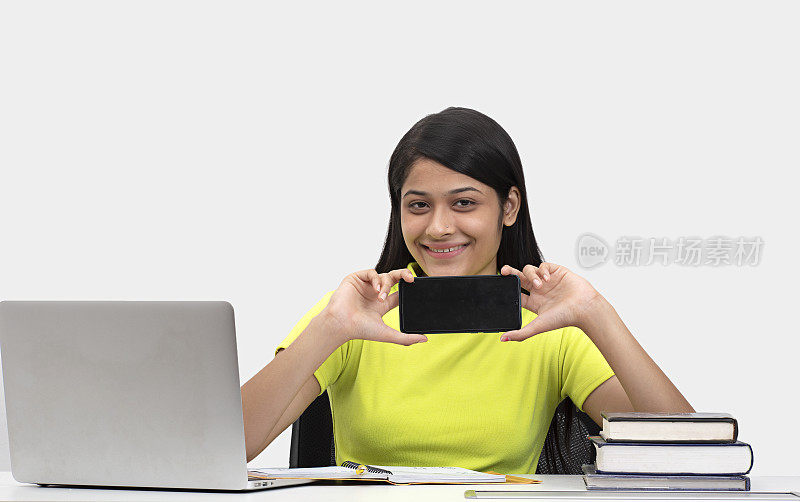 年轻女孩在家里学习，显示空白屏幕的手机库存照片