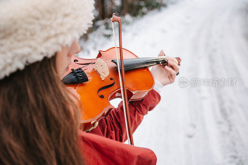 一位年轻女子在一个下雪天拉小提琴