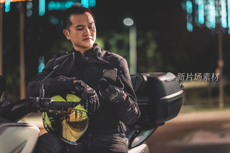 亚洲华人男子晚上在城市里骑着雅马哈摩托车