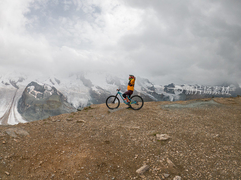 男性山地自行车爱好者欣赏风景，土路，远处的冰川