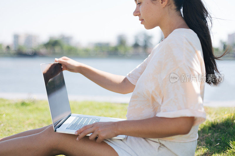 年轻女子在一个美丽的地方用笔记本电脑工作在大自然