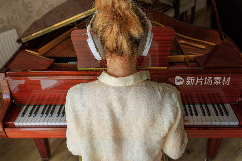 年轻女子戴着耳机听音乐，弹奏复古钢琴，生活方式