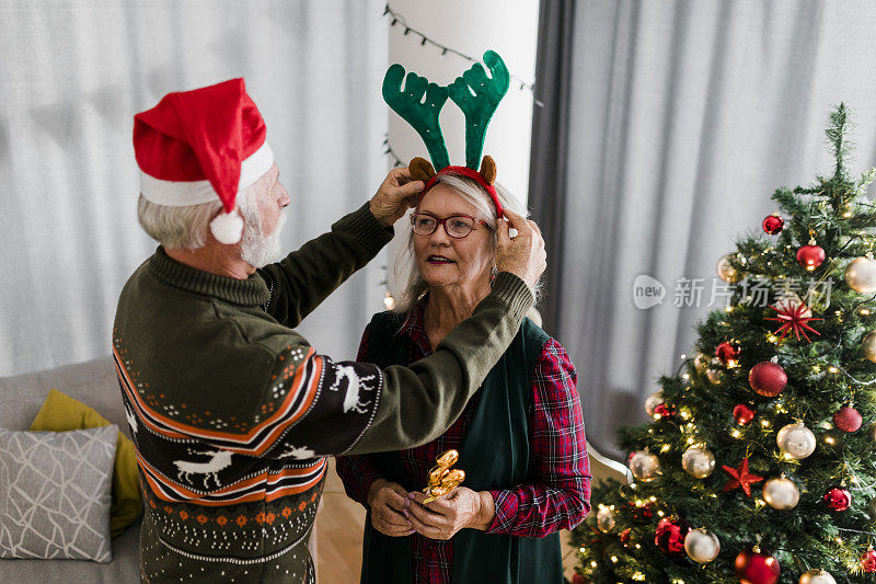 老夫妇试着戴上圣诞帽和驯鹿鹿角的服装，在家里一起开心地庆祝圣诞节