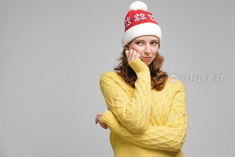圣诞妇女肖像的女孩戴着圣诞老人的帽子，人手势的相机和显示的情绪。工作室概念与人在灰色背景和复制空间。新年摄影