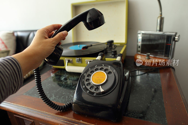 一只手拿起一部黑色古董拨号电话的听筒