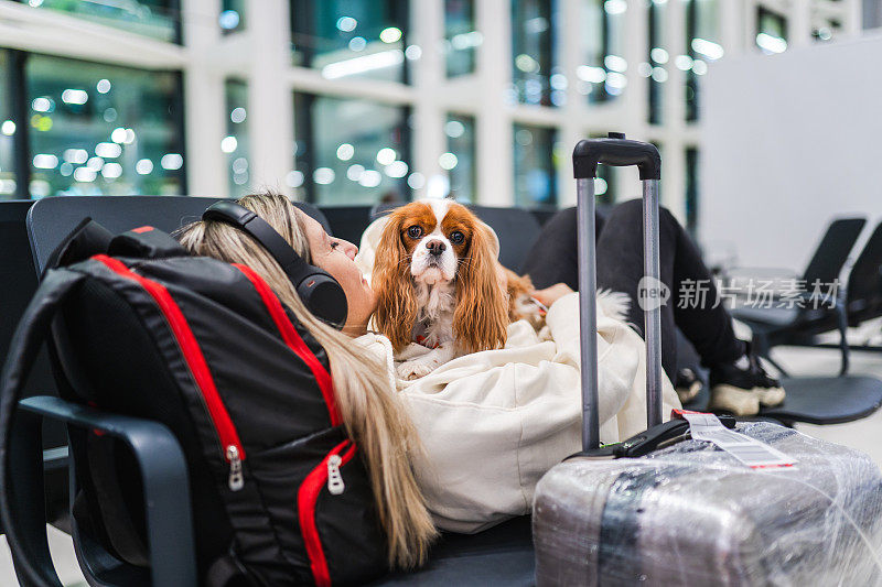 一名女子带着她的狗在机场等待她的航班