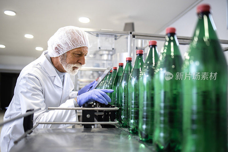 工厂技术人员在装瓶厂检测饮料质量。