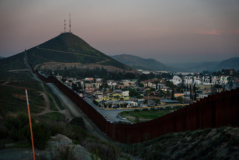 加利福尼亚特卡特和墨西哥特卡特之间的国际边界墙，靠近下加利福尼亚北部蒂华纳的黄昏，在令人惊叹的日落下，从美国俯瞰城市
