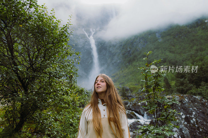 在挪威，一名女子凝视着风景优美的瀑布
