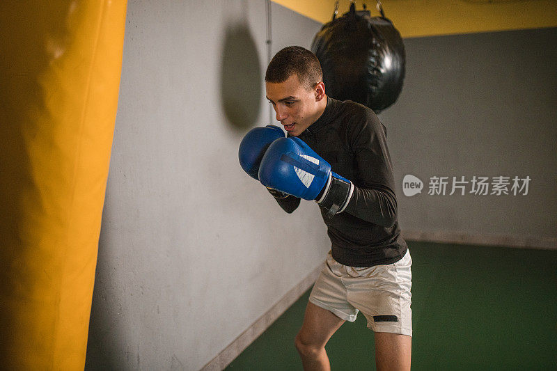 男拳击手在拳击馆训练，专注于变得更强壮