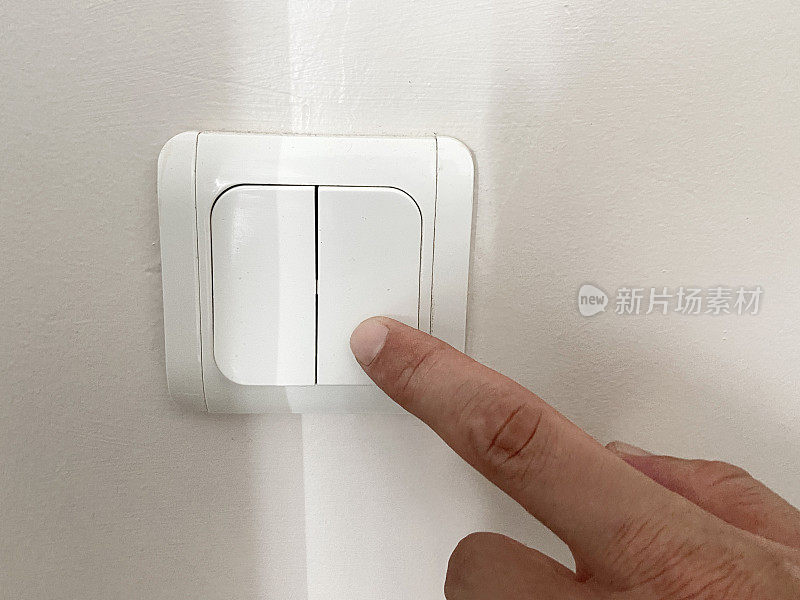打开或关闭电灯开关。手指按压墙上的电灯开关按钮