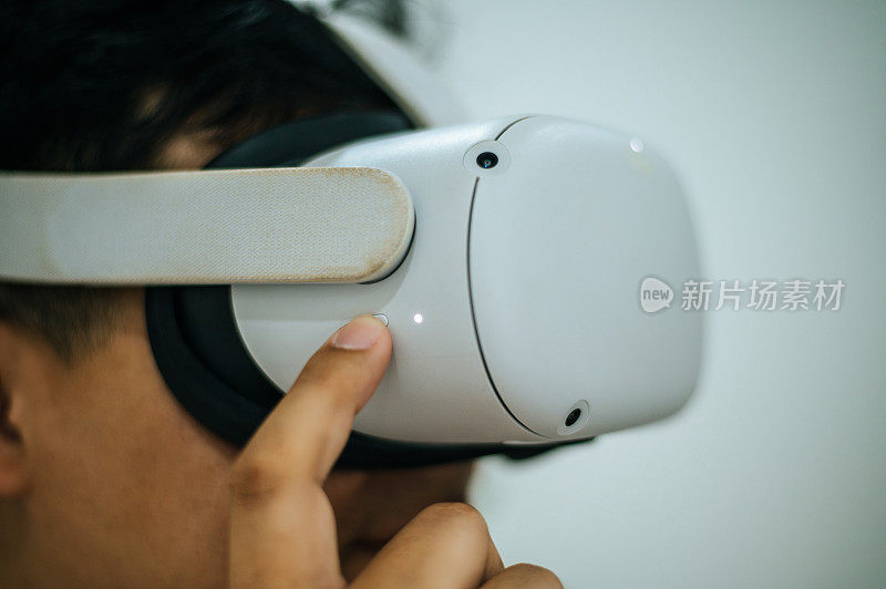 一个兴奋的亚洲男人在家里用VR眼镜探索虚拟现实