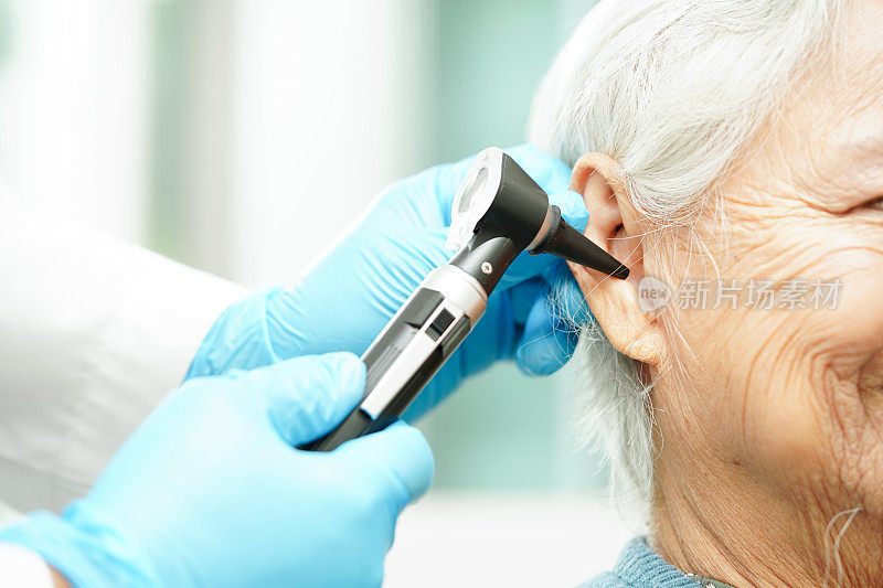 耳鼻喉科医生或耳鼻喉科医生用耳镜检查老年患者的耳朵，听力损失问题。