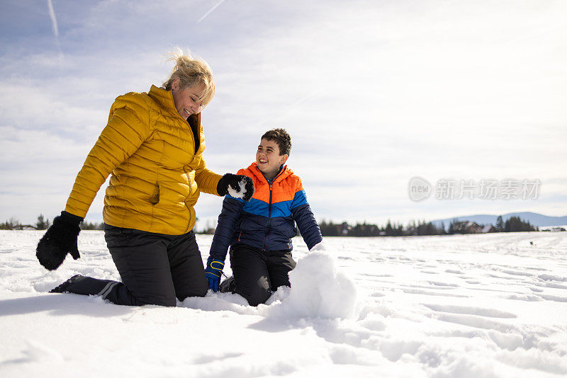 顽皮的高加索儿子和母亲在山上堆雪人