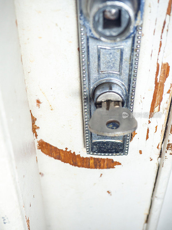 旧门的一部分。木头上的白漆正在脱落。表面油漆剥落。旧门把手。钥匙在门上的概念。