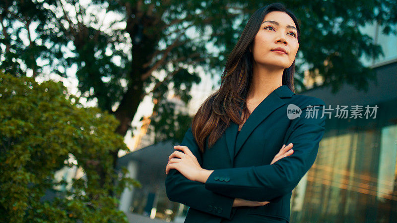 迷人自信的亚洲女性行政经理，身着西装的商务女性双臂交叉站立，在现代写字楼工作的职业经理