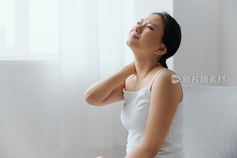 颈部疼痛。患有纤维肌痛的美丽年轻的亚洲女人在家里的室内客厅摩擦按摩紧张的肌肉。伤害，不良健康，疾病概念。酷炫报价横幅