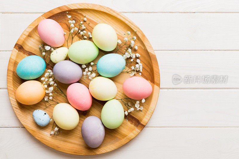 复活节作文快乐。复活节彩蛋在篮子里，在彩色的桌子上有吉思菲。自然染色彩色鸡蛋背景顶视图与复制空间