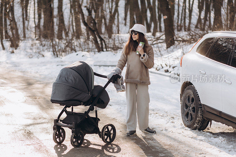 一位年轻的母亲在冬天推着婴儿车走着