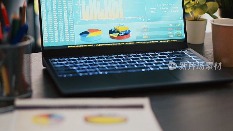 桌子上有财务报告，旁边是办公室里显示市场统计数据的笔记本电脑