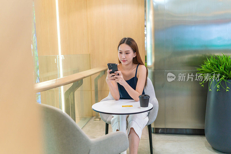 年轻的亚洲女性在咖啡厅用智能手机进行数字银行信用卡交易