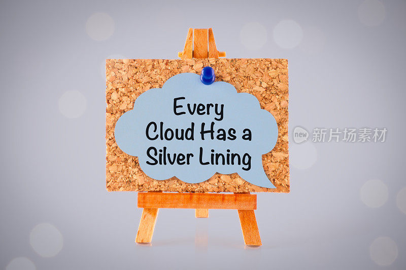 一个木制画架上的软木板上有一个蓝纸演讲泡泡，上面写着“乌云总有一线光明”。